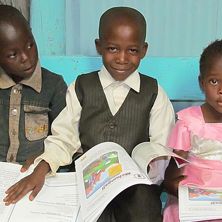 A young boy in Kenya reading an open Character Code for Life Bible study workbook.